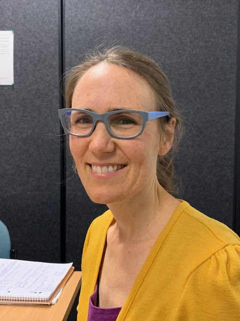 A woman smiles at the camera from a teaching desk